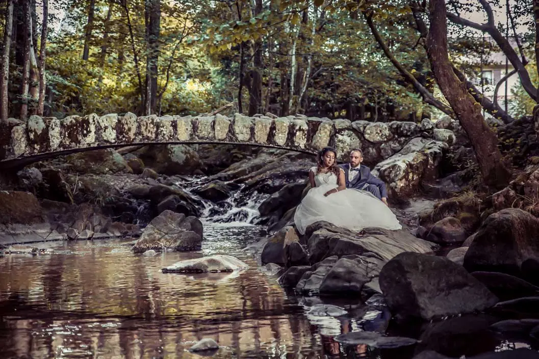 Couple assis à cote d'un ruisseau avec un petit pont
