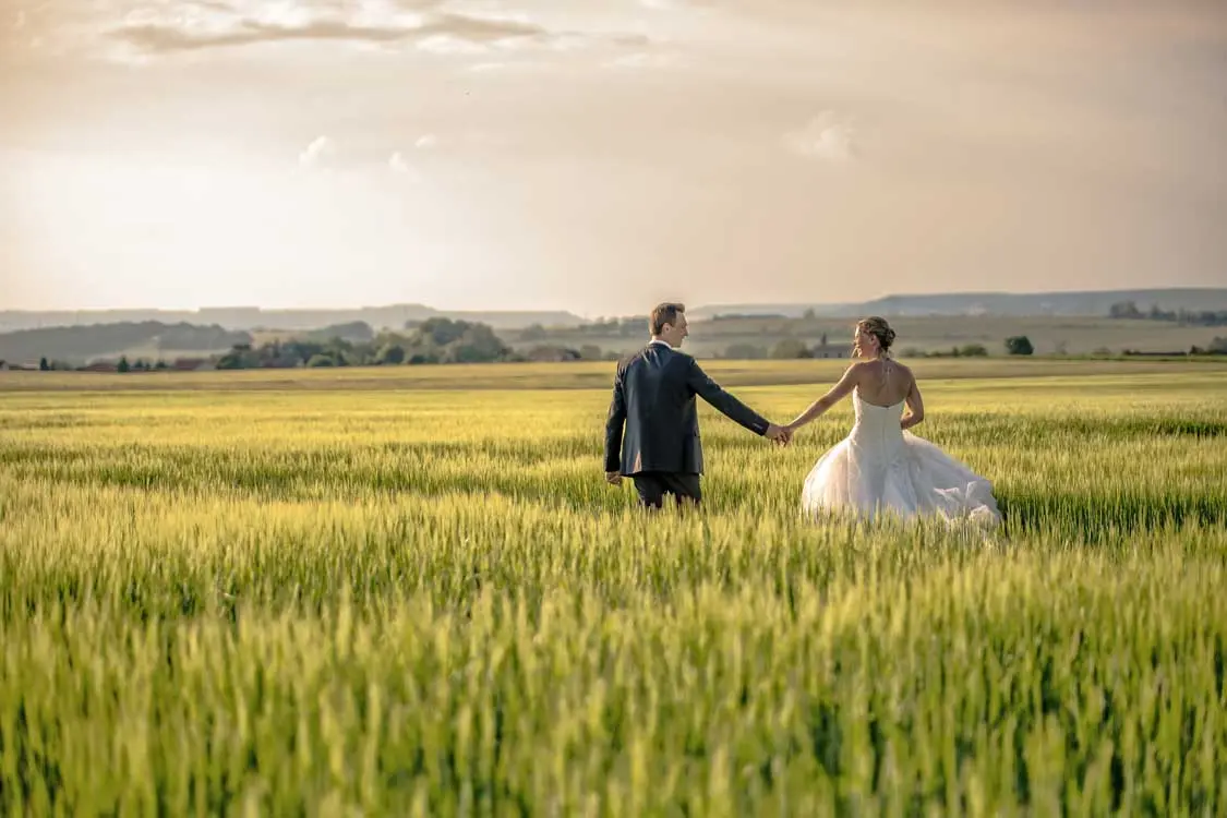 Couple qui marche dans les champs de blé main dans la main.