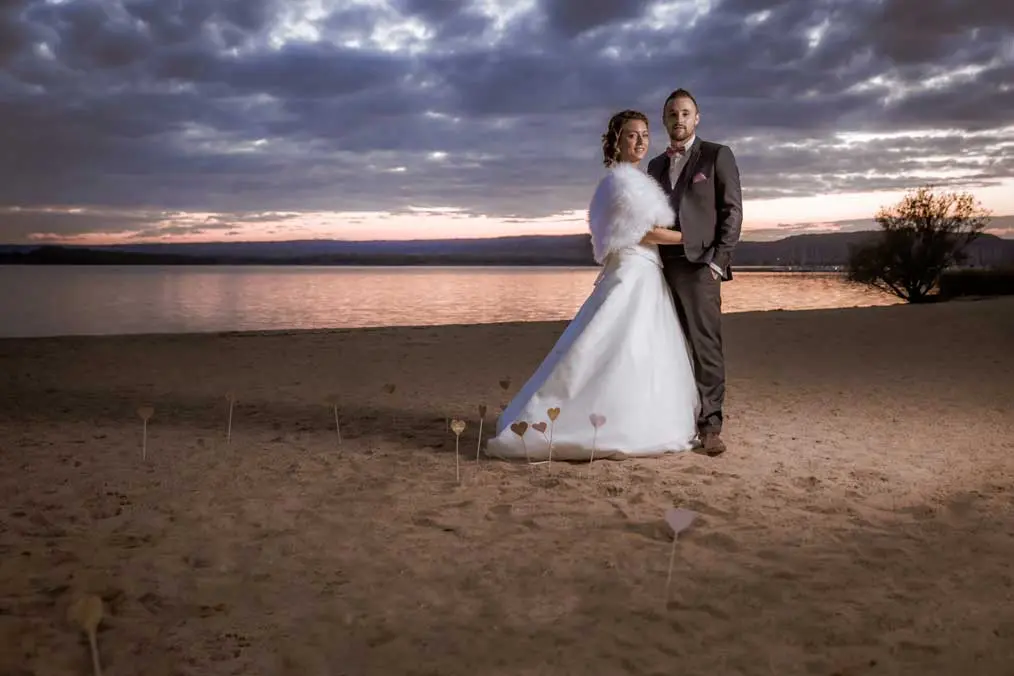 Couple qui se tient debout sur une plage avec un couché de soleil