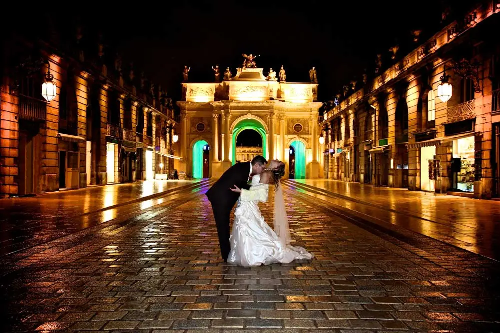 Couple qui s'embrasse de nuit sur une place.