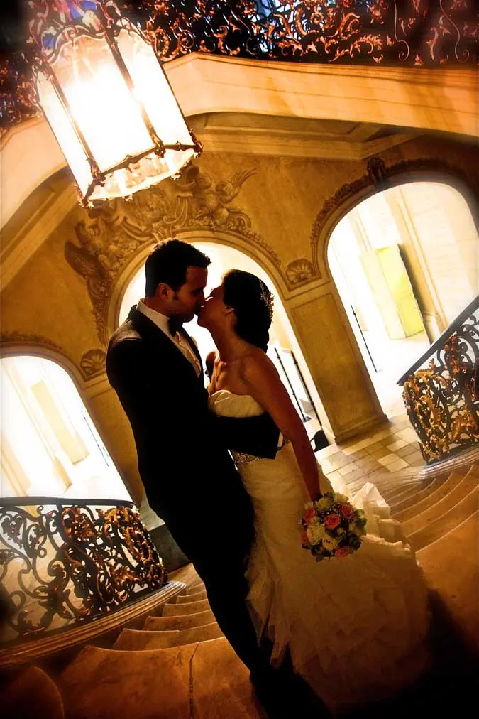 couple qui s'embrasse dans des escaliers Un gros luminaire au dessus