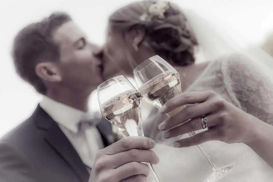 Couple s'embrasse un verre de champagne à la main pendant le vin d'honneur